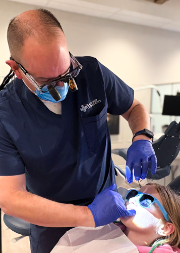 orthodontist providing treatment to patient in chair