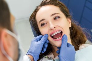 Orthodontist inspecting young woman's braces